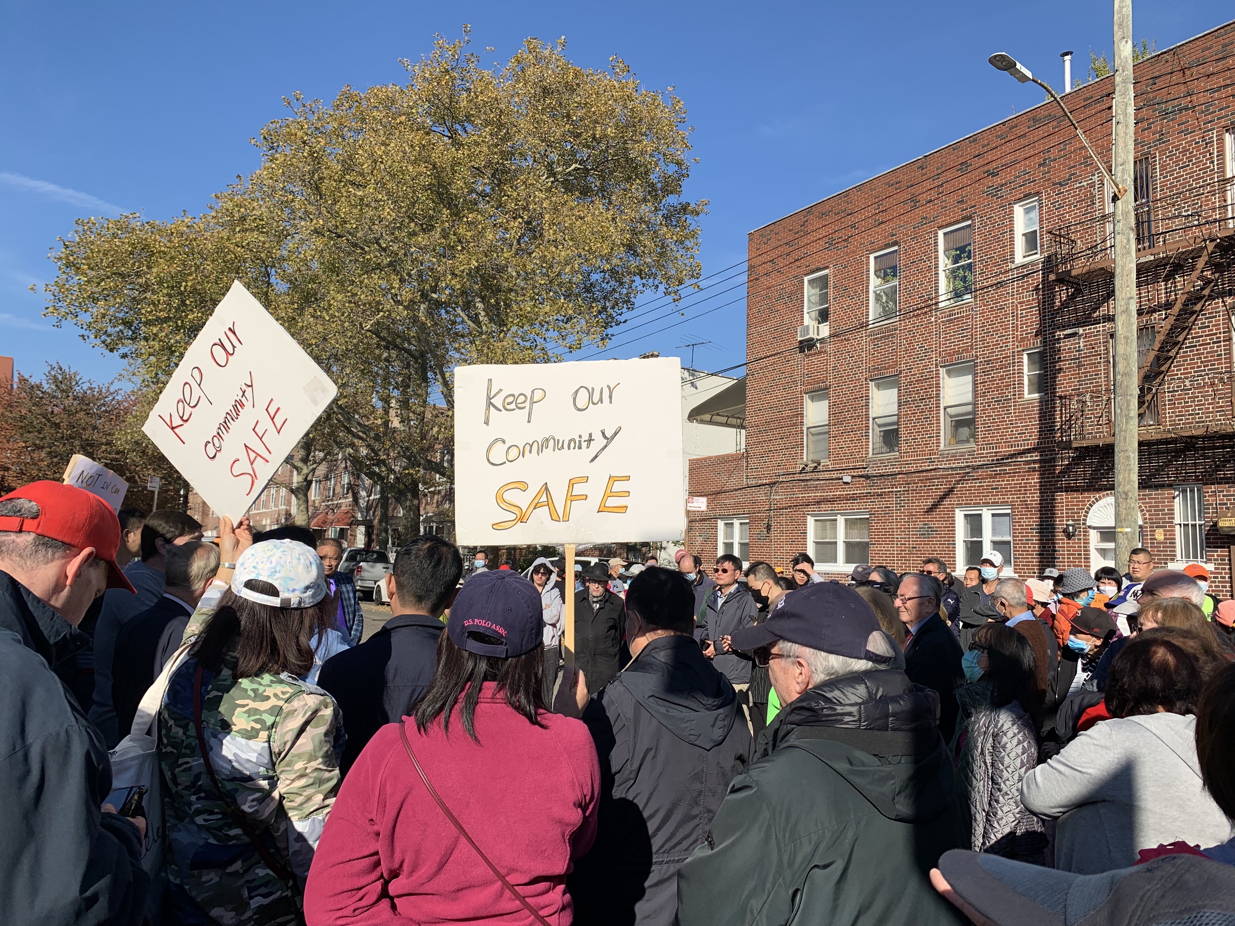 Rally attendees hold signs reading 'Keep our community safe' in opposition to a proposed family shelter in Bensonhurst